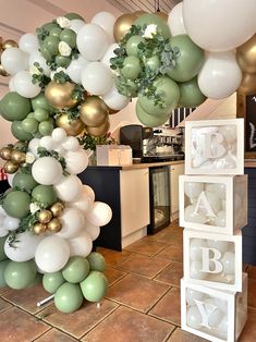 some balloons are hanging from the ceiling in front of a table with white and green decorations