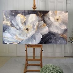 an easel with a painting on it in front of a white paneled wall