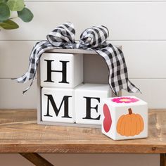 a wooden block with the word home on it and a pumpkin sitting in front of it