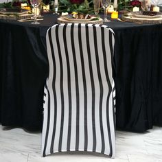 a black and white striped chair cover sitting in front of a table with wine glasses on it