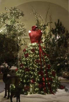 a christmas tree in the middle of a room with lights on it and a dog standing next to it