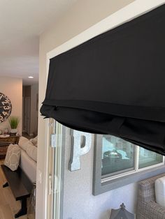 a living room filled with furniture and a large window covered in black fabric coverings