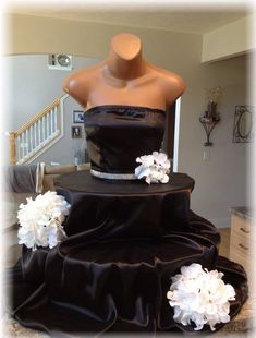 a mannequin wearing a black dress with white flowers on the bottom and sides