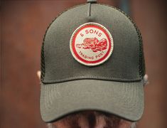 Introducing our Trucker Badge Cap in army green, the perfect addition to any casual outfit. Made with a main body of 100% cotton and poly mesh rear, this cap is perfect for keeping cool in warmer weather. Featuring a unique woven patch that adds a touch of ruggedness and character, this cap is designed to be worn with pride. The adjustable back ensures a comfortable fit for all head sizes, and the six rows of top stitching on the peak add an extra touch of durability. The interior printed tape i Printed Tape, Half Zip Top, Watch Cap, Racing Green, Red Label, Keep Cool, The Peak, Tracksuit Bottoms, Pocket Tshirt