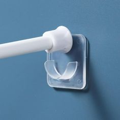 a toothbrush holder attached to a blue wall with a white plastic tube in it