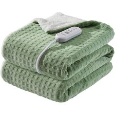 two green towels stacked on top of each other with a thermometer attached to them