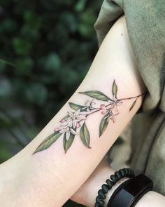 a woman's arm with flowers and leaves on it