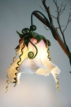 an octopus lamp hanging from a tree branch in front of a white wall and ceiling