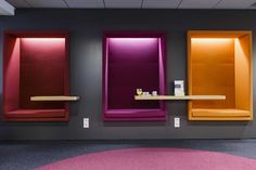 an empty room with three different colored shelves on the wall and a table in front of it