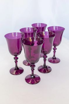 purple glass goblets lined up on a white surface