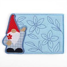 an embroidered patch with a gnome on it's face and flowers in the background