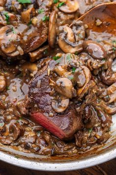 steak with mushrooms and gravy in a skillet on a wooden table, ready to be eaten