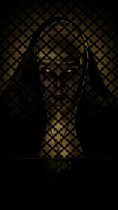 a creepy looking person in the dark with headphones on, behind a chain link fence