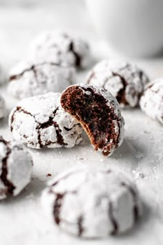 chocolate crinkle cookies with powdered sugar are on a white surface next to a cup of coffee