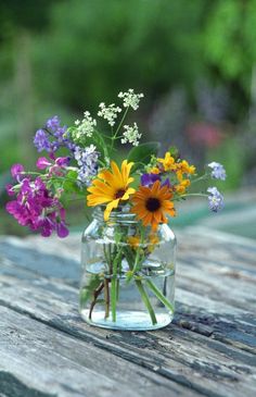 a jar filled with flowers sitting on top of a wooden table