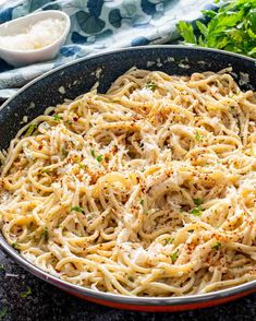 a pan filled with pasta and parsley on top of a table