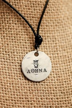 "PRODUCT INFORMATION: - Made on a 1 inch aluminum blank (wearer friendly) - Hangs on a black adjustable cord, about 26 inches at the largest setting - The name \"ATHENA\" (in Greek) and an owl are stamped on the pendant - Pendant made to look battered as if it has been in battle. This may include indentations and scuff marks. - These are HANDMADE so they will not be 100% exact copies of what you see in the picture. SHIPPING INFORMATION: - These are not pre-made meaning that I make them as they a Piper Mclean, Flan, Percy Jackson, Washer Necklace, Etsy Accessories, Accessory Gift, Jewelry Necklaces, Thing 1, Stamp