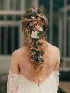 a woman with flowers in her hair wearing a white dress and looking out the window