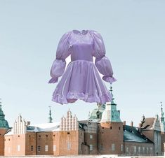 a giant purple dress hanging from the side of a building in front of a castle