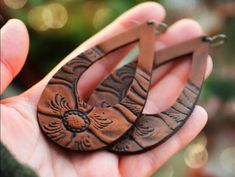 a person holding two wooden earrings in their hand