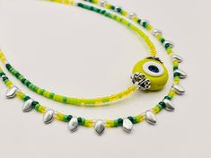 This dainty and whimsical gradient evil eye necklace is both sophisticated and understated. The handmade yellow and white evil eye is crowned with two pewter beads. I used Japanese seed beads in sunny bright yellow, acid green, meadow green and forest green, silver and translucent white to build the gradient colors enhancing the handmade bead. Silver gekko glass beads with their triangular shape add just the right amount of sparkle and edge to this design. Evil eye is believed to protect its own Yellow Tiny Beads Festival Jewelry, Yellow Tiny Beads Jewelry For Festival, Adjustable Silver Evil Eye Necklace, Adjustable Sterling Silver Evil Eye Necklace, Yellow Dainty Necklace Adjustable, Dainty Handmade Yellow Jewelry, Dainty Yellow Jewelry With Tiny Beads, Yellow Jewelry With Tiny Beads For Gift, Dainty Yellow Adjustable Necklace