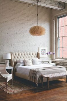 a bedroom with white brick walls and a large bed in the middle, along with a rug on the floor