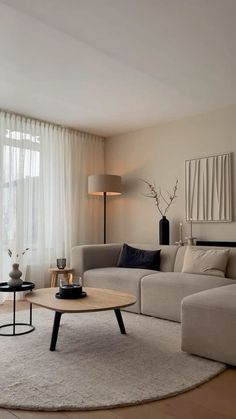 a living room filled with furniture and a large window covered in white drapes