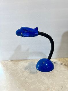 a blue lamp sitting on top of a table next to a white wall and floor