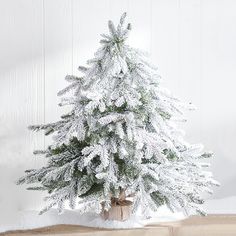 a small white christmas tree sitting on top of a wooden table next to a book