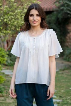 Gossamer-light white cotton voile becomes a wonderfully feminine top in the talented hands of India's Seems Shah. The blouse features flutter sleeves, ruffled shoulder accents and pintucks on the five-button bodice. Feminine Short Sleeve Peasant Top For Daywear, White Feminine Peasant Top With Short Sleeves, White Feminine Short Sleeve Peasant Top, Elegant Short Sleeve Peasant Top For Summer, Feminine Cotton Blouse With Butterfly Sleeves, White Short Sleeve Peasant Top With Ruffles, White Feminine Blouse With Butterfly Sleeves, Feminine White Butterfly Sleeve Blouse, Feminine Top