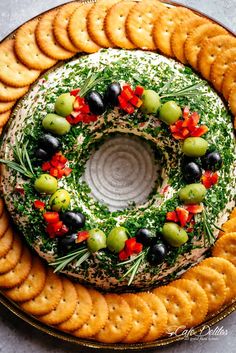 a platter filled with crackers, olives and rosemary sprinkled wreath