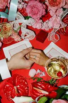 two hands holding each other over a table with flowers and napkins on top of it