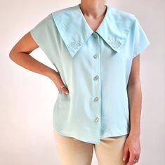 Gorgeous vintage blouse in aqua blue with beautiful chelsea collar. It has short dolman sleeves, floral collar embellishment and five round buttons. It is made from a lightweight and smooth polyester fabric. Perfect blouse for everyday or special occasions. Made by C&A. 100% polyester. Labelled as size 16 UK, 40, would Medium to Large size. Measurements when laid flat are: Pit to pit: 52cm Waist: 50cm Hemline: 54cm Length: 61cm. Excellent condition. B. Light Blue Short Sleeve Button Blouse, Light Blue Short Sleeve Blouse With Buttons, Daywear Tops With Peter Pan Collar And Buttons, Light Blue Fitted Top With Collar, Peter Pan Collar Top For Daywear, Light Blue Collared Blouse With Buttons, Vintage Fashion Collared Blouse With Buttons, Vintage Collared Tops With Buttons, Vintage Collared Button Tops