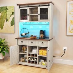 a cabinet with shelves and drawers in the middle of a wooden floored room next to a potted plant