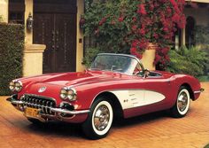 an old red and white car parked in front of a house