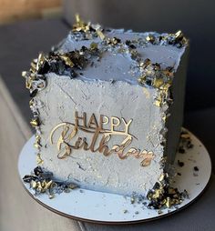 a white and gold birthday cake sitting on top of a plate