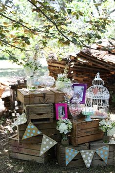 a table topped with wooden crates covered in flowers and birdcage filled with photos