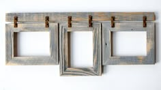 three wooden frames hanging on a white wall with metal clips to hold them in place