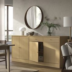 a wooden cabinet with a mirror and vase on it in front of a window next to a chair