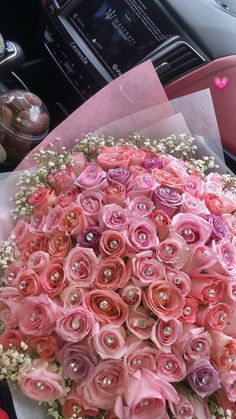 a bouquet of pink flowers sitting on top of a table next to a cell phone