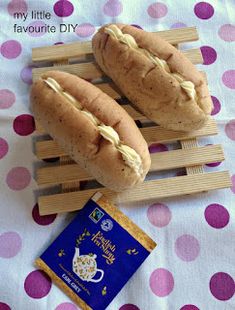 two hot dogs sitting on top of a wooden rack next to a packet of peanut butter