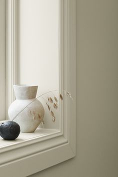 a white vase sitting on top of a window sill next to a black rock