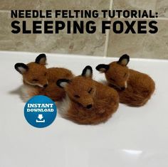 three needle felted foxes sitting on top of a white sink next to a tile wall