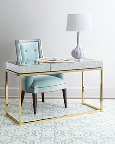 a blue chair sitting next to a desk with a mirror on it and a lamp