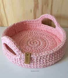 a pink crocheted basket sitting on top of a table