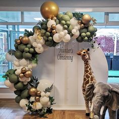 an elephant and giraffe are standing in front of a balloon arch