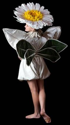 a woman with a flower on her head is standing in front of a black background