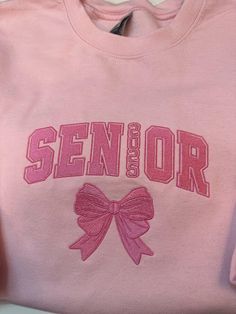 Celebrate your senior year in style with this cozy embroidered sweatshirt, perfect for the Class of 2025! Made from high-quality, soft material, this sweatshirt features 'Seniors 2025' beautifully stitched across the chest, making it a must-have for any graduating senior. Available in multiple colors and sizes, it's great for everyday wear, school events, or as a memorable keepsake. Whether you're buying it for yourself or as a gift for a senior, this sweatshirt is a comfortable and stylish way to commemorate the Class of 2025! *Enter thread color in personalization box and I will use two or three shades of the color you choose to create the beautiful shadow effect of the letters and bow.  Size and color charts are available in listing photos. Sweatshirt Type: Gildan Fleece lined  *Please Aesthetic Senior Shirts, Senior Year Sweatshirts, Graduation Sweatshirts Ideas, Seniors Hoodies, Senior Sweatshirts Ideas, Senior Sweater, Senior Basket, Senior Clothes, Senior Hoodies Design Ideas