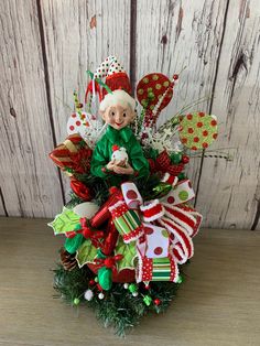 a christmas wreath with an elf on top and candy canes in the middle, sitting on a wooden surface