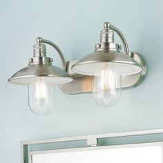 two light fixtures are mounted on the wall above a bathroom mirror and medicine cabinet in a blue walled room